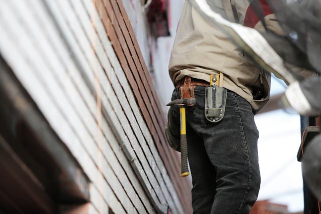 person on a ladder with a hammer and tools