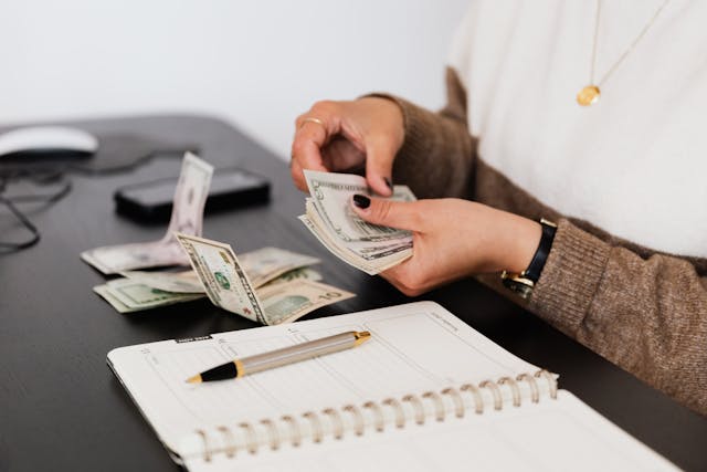 person counting cash with notebook laid out in front of them
