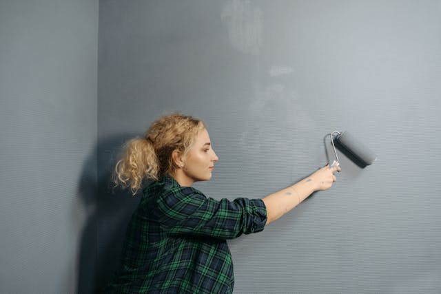 woman painting wall dark grey