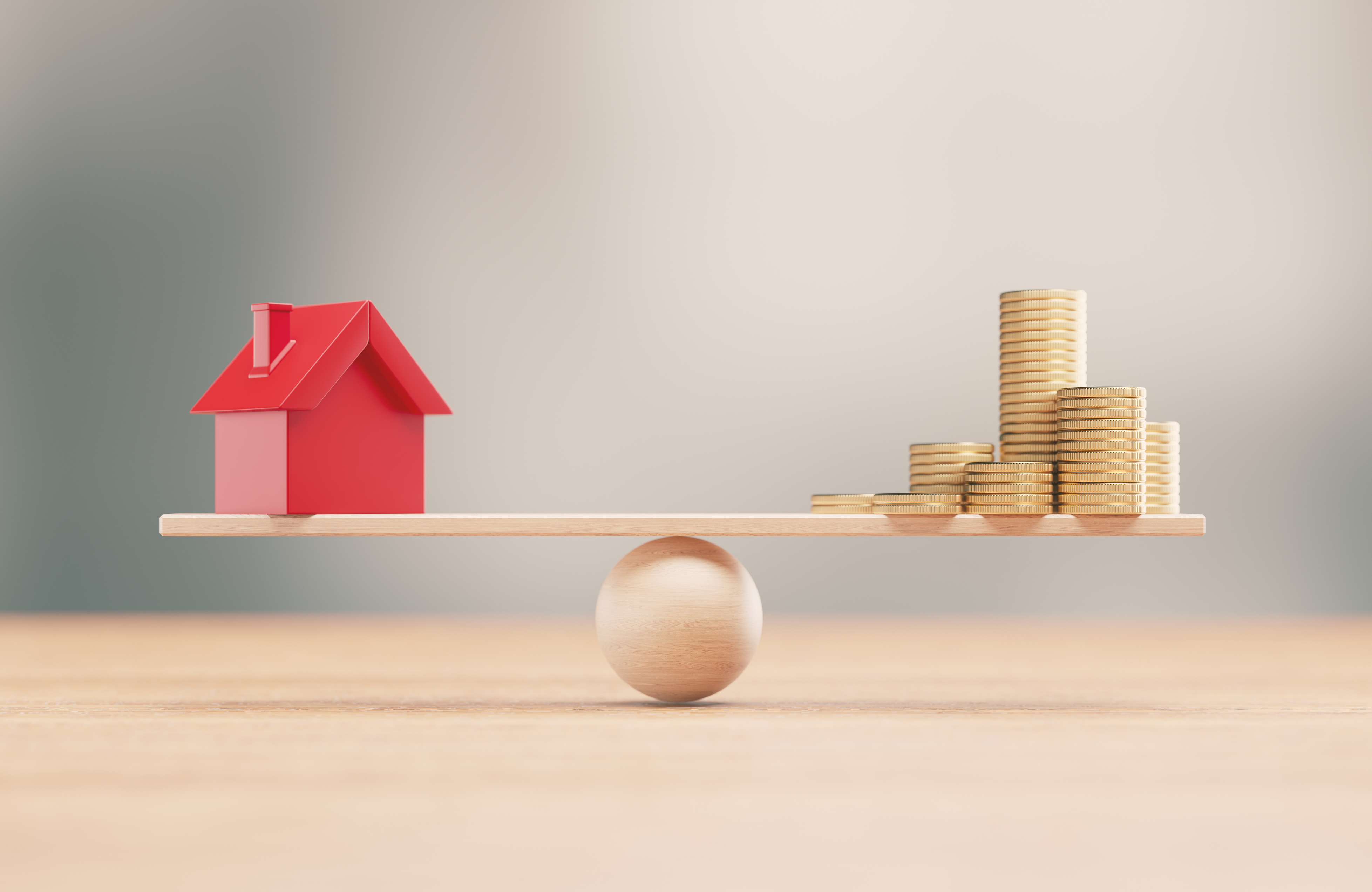 red-house-and-stacked-coins-balanced-on-wooden-board